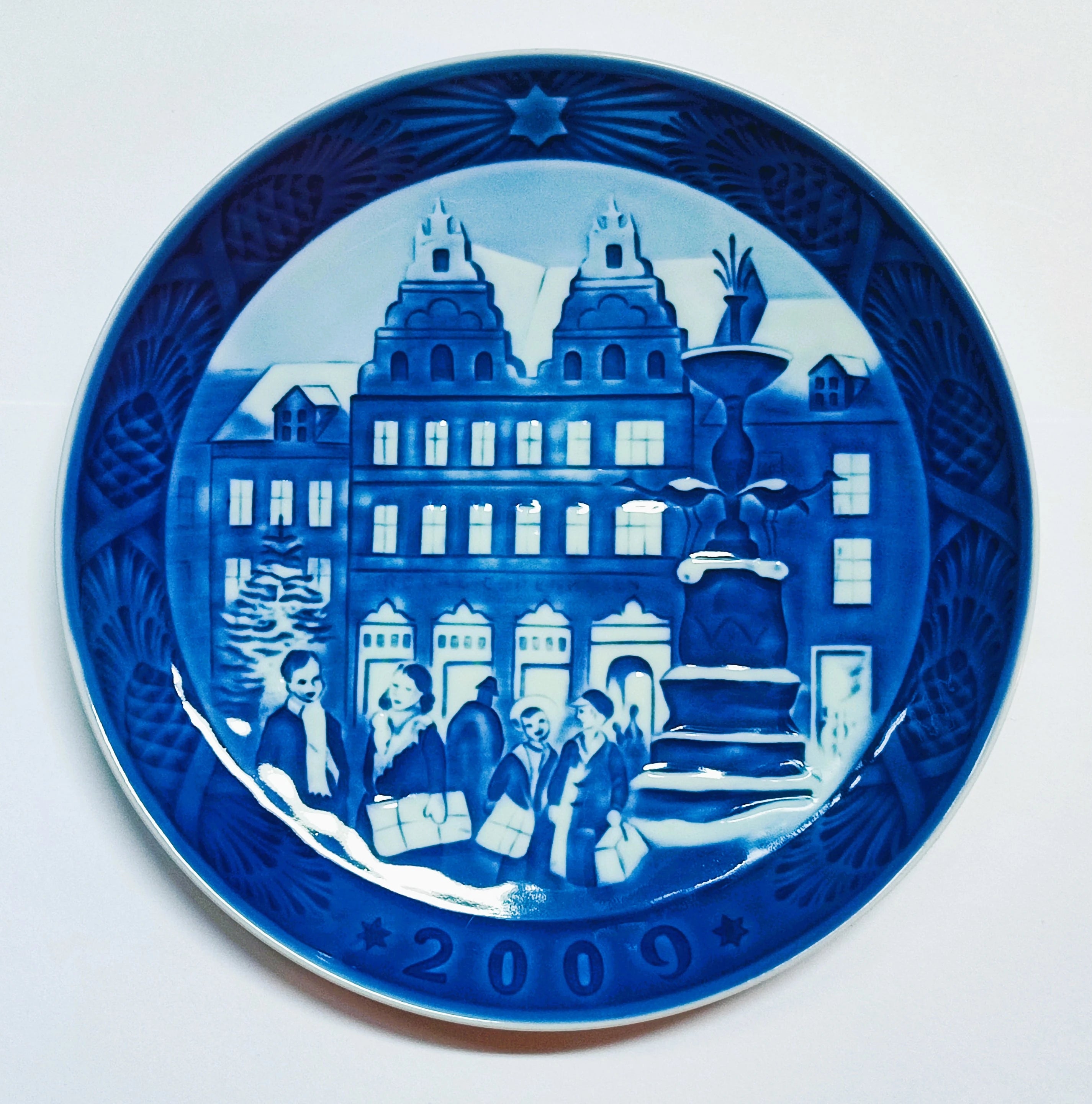 Piatto di Natale Royal Copenhagen diametro 18 cm · Blu; Bianco · Sven Vestergaard · Natale ad Amagertorv · RC-CP-2009