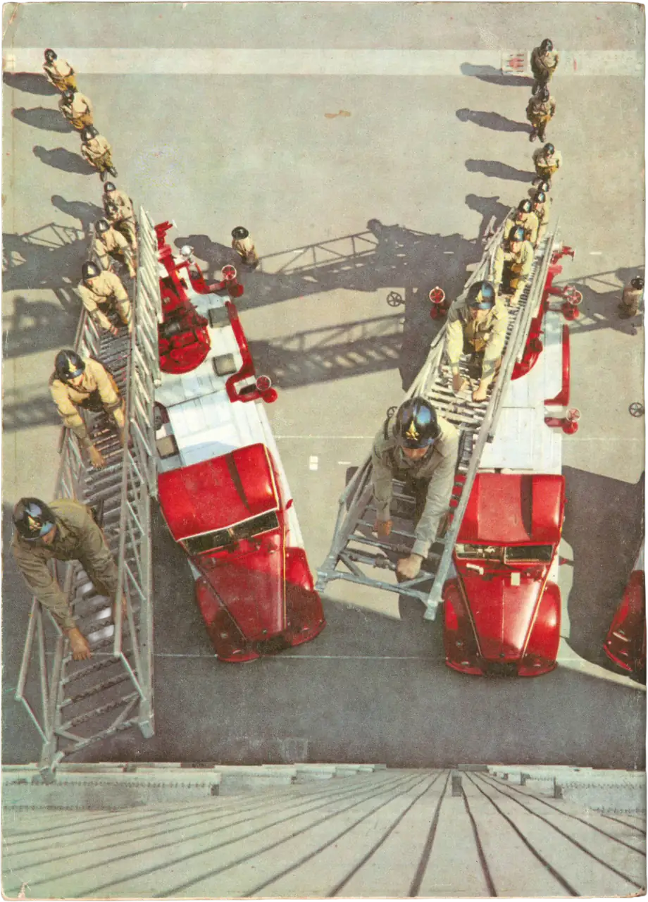 Fotografia zenitale a tutta pagina che ritrae due autoscale rosse dei Vigili del Fuoco schierate durante un'esercitazione. Diversi pompieri in uniforme storica e casco sono posizionati lungo le scale estese e a terra, creando una composizione geometrica di forte impatto visivo.