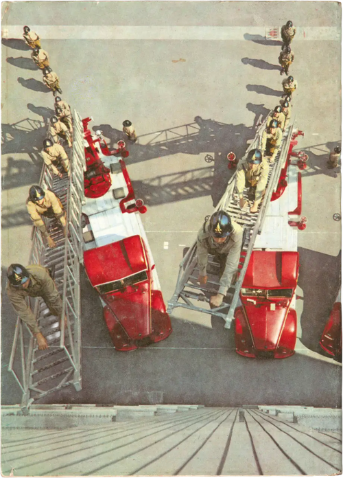 Fotografia zenitale a tutta pagina che ritrae due autoscale rosse dei Vigili del Fuoco schierate durante un'esercitazione. Diversi pompieri in uniforme storica e casco sono posizionati lungo le scale estese e a terra, creando una composizione geometrica di forte impatto visivo.